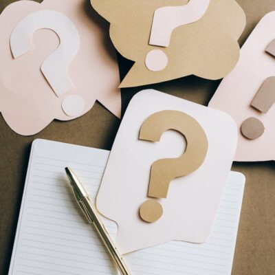 Flat lay of question mark paper crafts on a notebook, symbolizing questions and ideas.