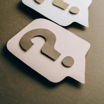 Two paper craft question marks on speech bubbles create a conceptual visual.